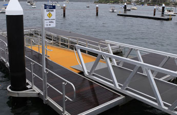 A floating jetty Sydney with a wheelchair-accessible ramp and caution sign, set amidst the serene waters.